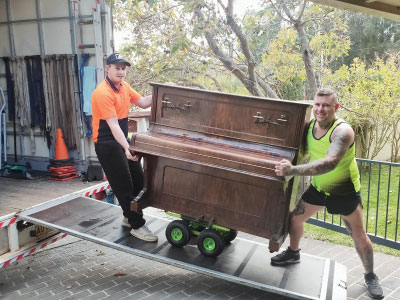 The Wyong Removals & Storage team pushing a piano into the back of their truck